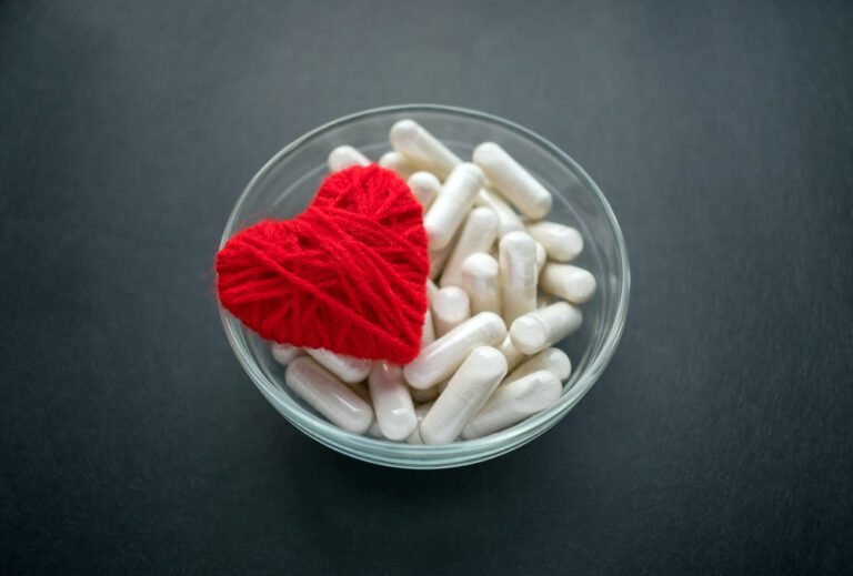 Capsules végétales blanches et coeur en fil rouge dans un bol en verre