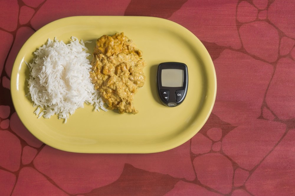 Un glucomètre pour mesurer la glycémie à côté d'une portion de riz au poulet