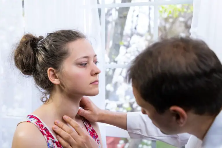 Médecin inspectant, effectuant un examen de palpation d'une jeune femme atteinte de la maladie de Graves, de symptômes d'hyperthyroïdie, de goitre thyroïdien élargi et d'ophtalmopathie à l'hôpital