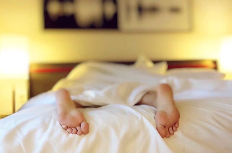 Personne allongée sur un lit recouvrant une couverture blanche
